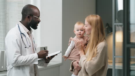 Médico-Consultando-A-Una-Mujer-Con-Un-Bebé-En-La-Clínica